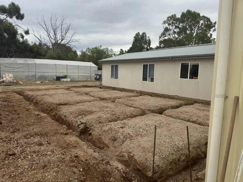 House enclosed by a fence and dirt, emphasising its architectural design and engineering aspects.